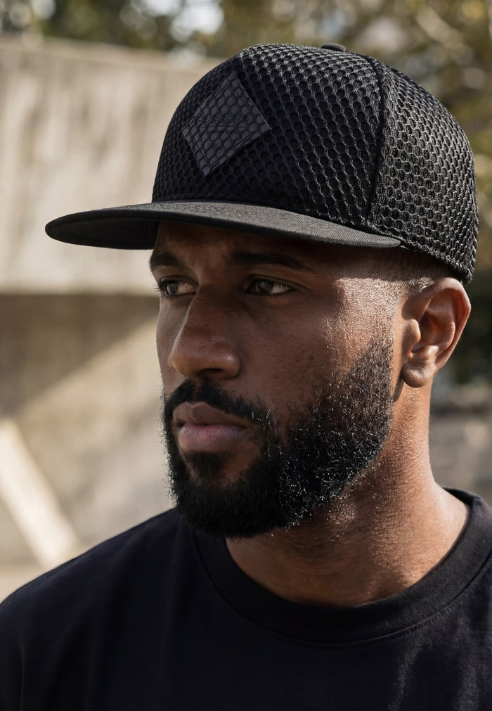 Man wearing a black cap with a textured pattern, looking off to the side.