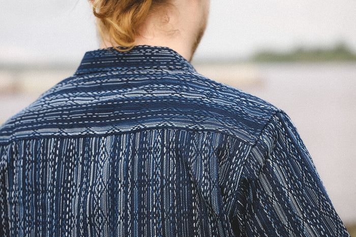 Person wearing a blue patterned shirt with a blurred background
