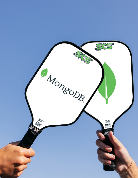 Two custom pickleball paddles with MongoDB and SCS branding against a clear blue sky.