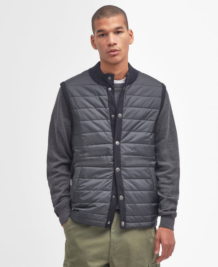 Man wearing a gray quilted jacket with black trim on a light gray background