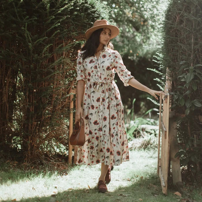 Woman in a floral dress and hat standing in a garden