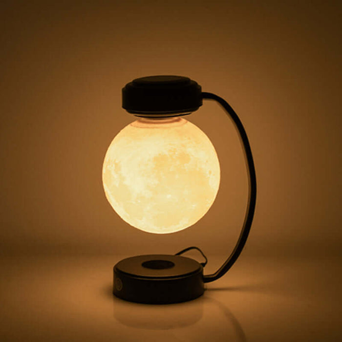 Magnetic levitating moon lamp glowing softly while floating in mid-air against a dark background.