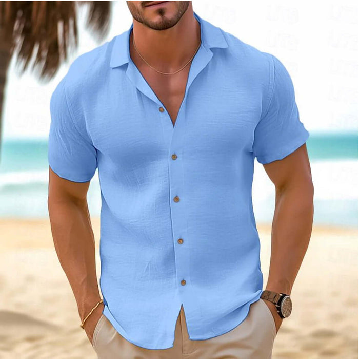 Men Short-Sleeved Button-Down Summer Shirt in light blue worn by a man on a beach background.