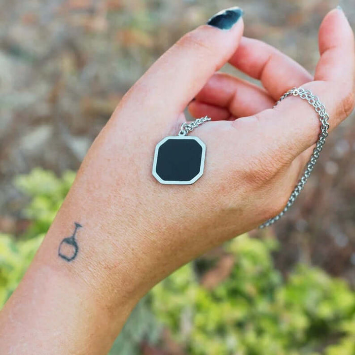 Metal Geometric Block Magic Necklace worn on hand, featuring a unique octagonal pendant with black accent.
