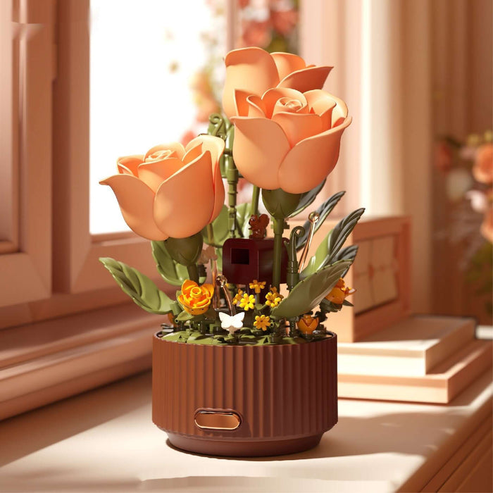 Preserved Flower Building Blocks Motion Flowers Model with orange roses and decorative elements in a pot by a window.
