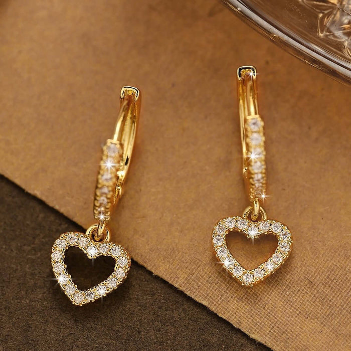 Retro Heart-shaped Pendant Ring Zircon Earrings in gold with sparkling heart design on a brown background.