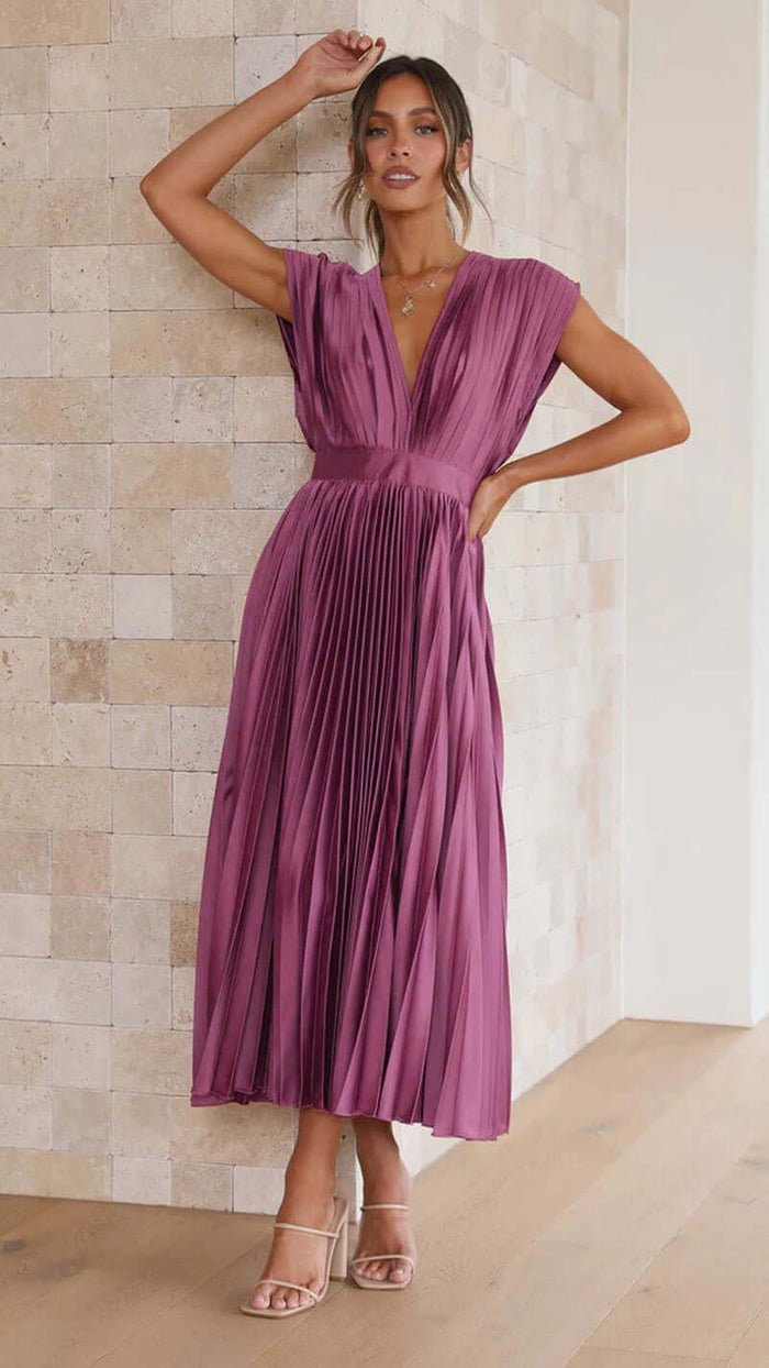 Model wearing Summer V Neck Pleated Sleeveless Maxi Dress in pink, standing against a textured wall.