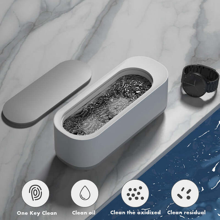 Ultrasonic High Frequency Jewelry and Glasses Cleaner with water and watch on marble surface.